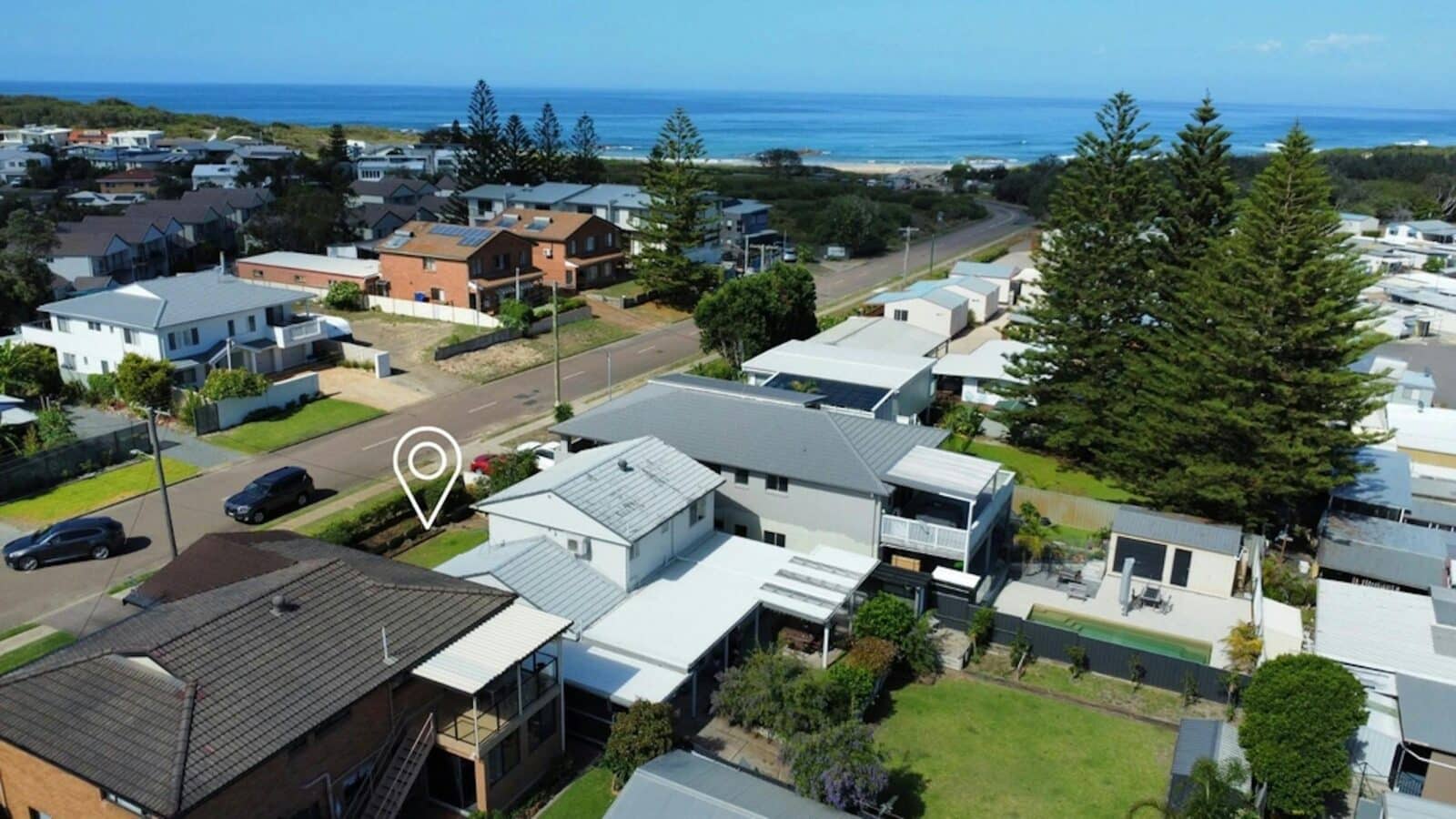 Aerial drone photo showing the house with a lush backyard and being a close level walk to the beach