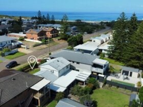 Aerial drone photo showing the house with a lush backyard and being a close level walk to the beach