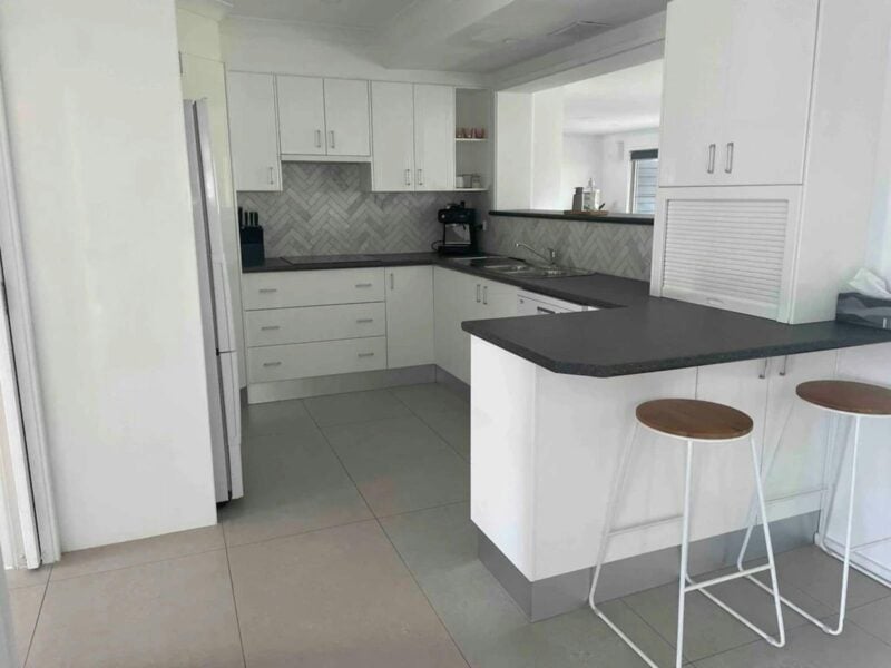 A modern kitchen with a clean, minimalist design. The floor is covered with large, light-grey tiles.