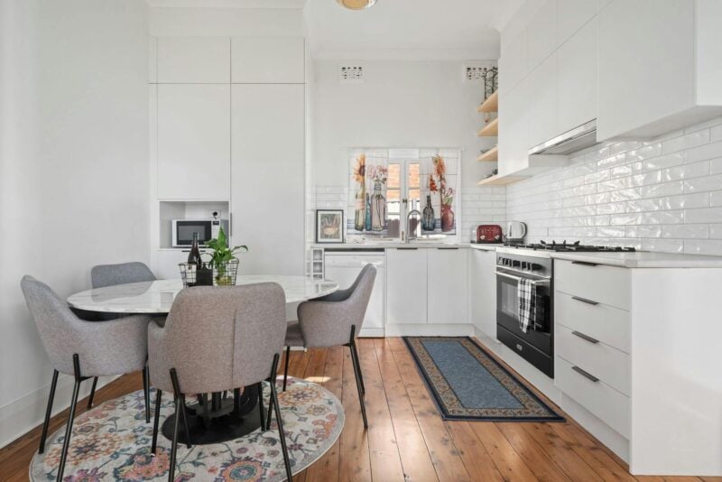 Modern kitchen, newly renovated with modern appliances and white tiles. Dining table with 4 chairs.