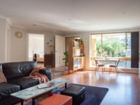 Large sun-lit room with lounge, coffee table, smart TV and Kitchenette.