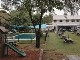 Garden area with children's playground and Pool with trees and tables on grassed area