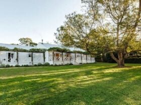 Image of front view of property, a large grassed area leads you to an all white home.