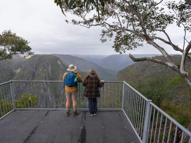 Two people admiring the view of surrounding mountains from Adams lookout, Bungonia National Park.
