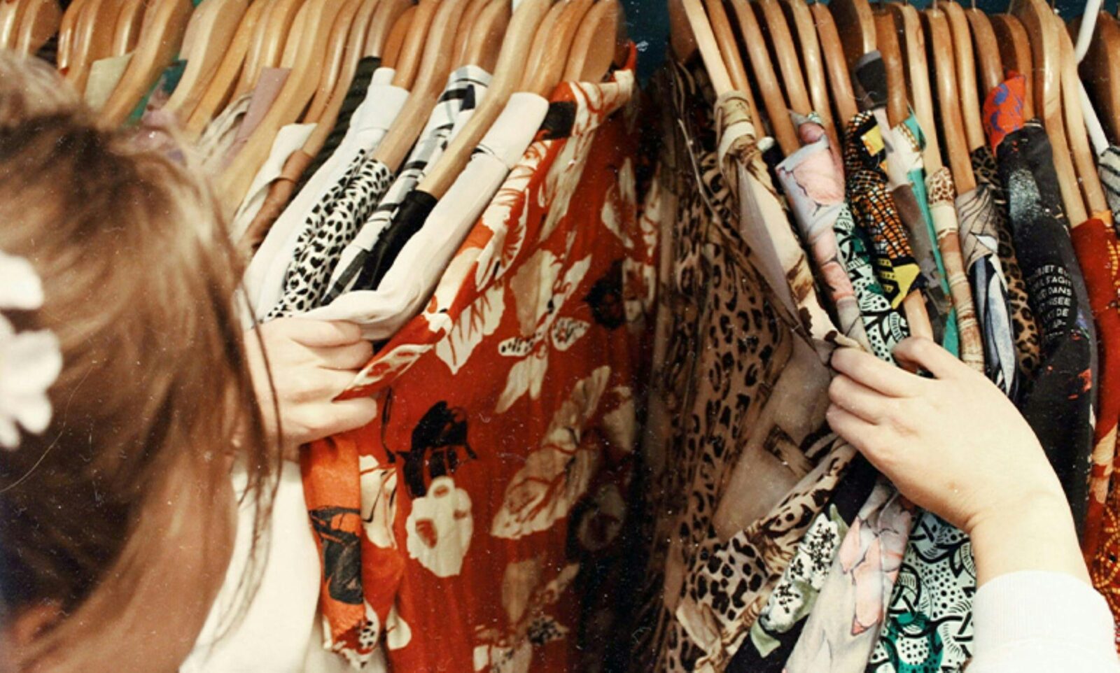 Image of a woman sorting through a clothing rack of dressesseries of dresses on a rack
