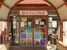 entry door to ACCKP, welcome sign sits above the door way and images of flora are on the door.