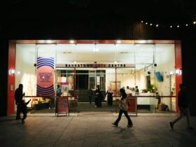 a few people are walking inside and in front of a building at night
