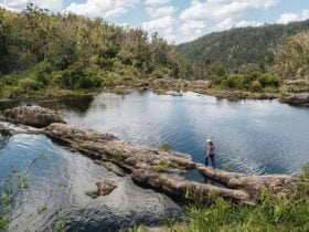 Person walking over rocks by rockpools in Boonoo Boonoo National Park. Photo: Harrison Candlin