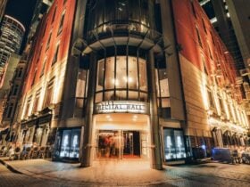 Night view of City Recital Hall entrance, illuminated facade with glass canopy and people entering,