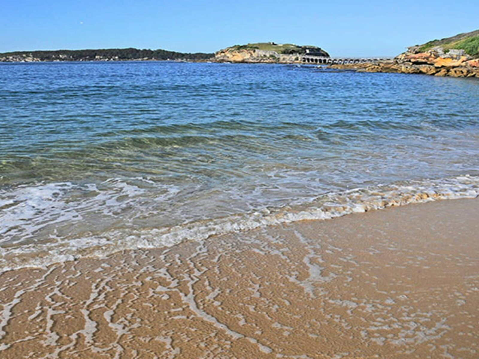 Gentle waves lap Congwong Beach, with Bare Island in background. Photo: Kevin McGrath/OEH.