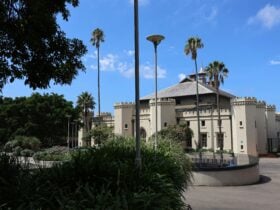 A white building with turrets, bordered by plants