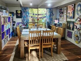 A table with 8 chairs in an art room filled with art and art supplies
