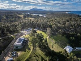Drone image of the Four Winds site featuring bushland, mountains and water surrounding