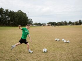 A soccer player is on the field and kicks a soccer ball