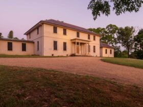 Large historic building stands prominantly with the sun going down in the background.