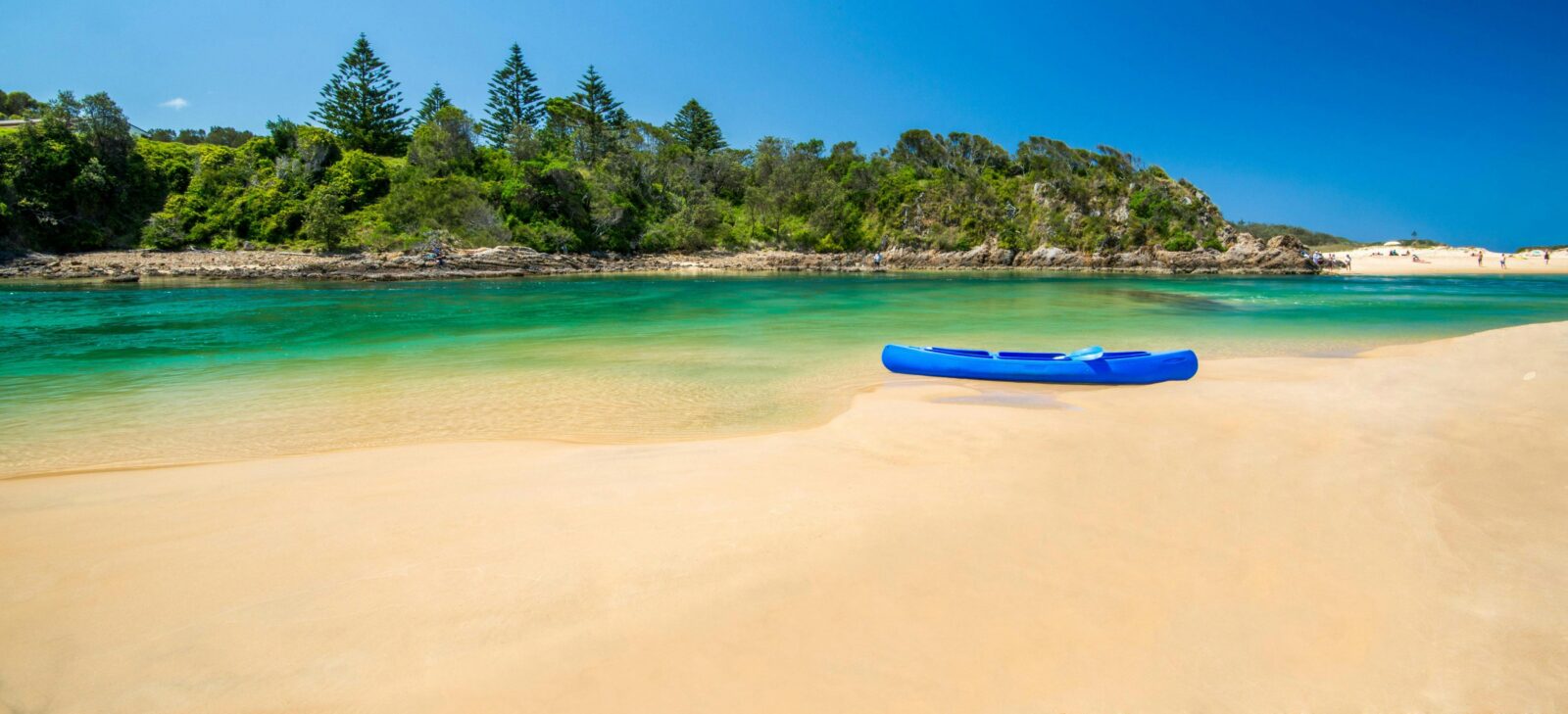 A blue kayak on the sand next to a lake