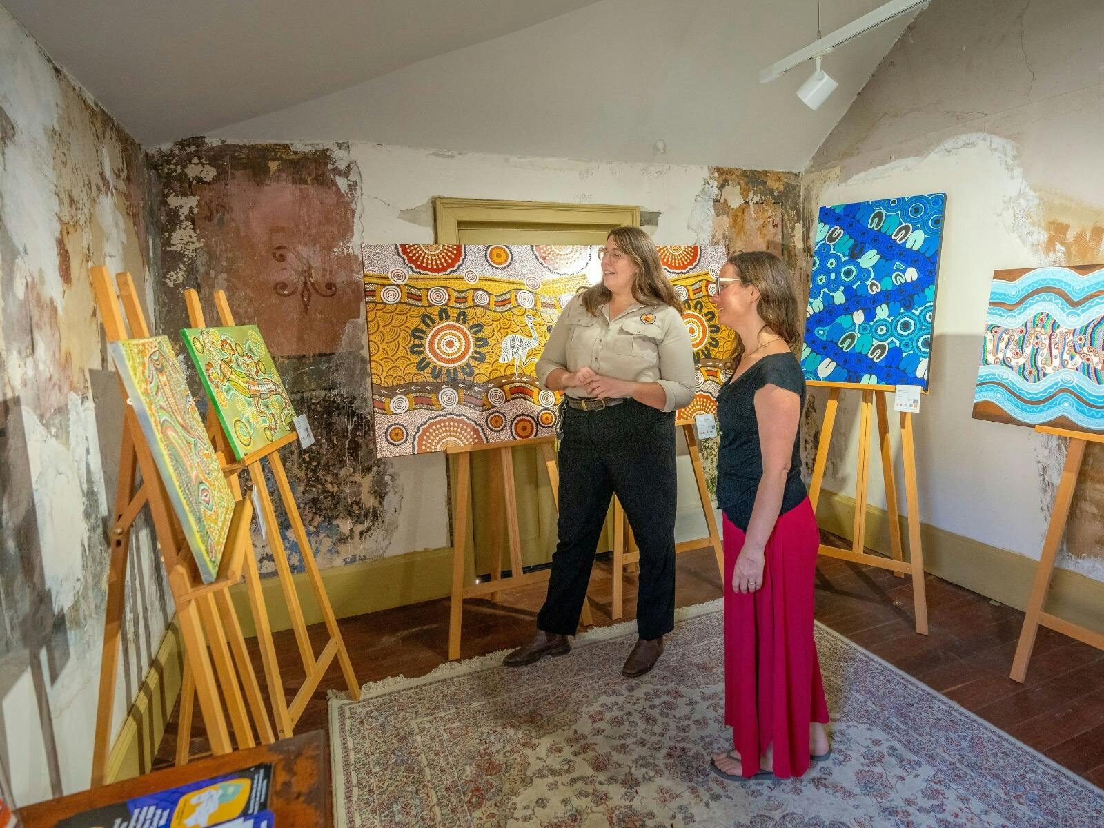 Visitor and NPWS officer look at artworks at Kew Y Ahn Aboriginal Gallery at Hartley