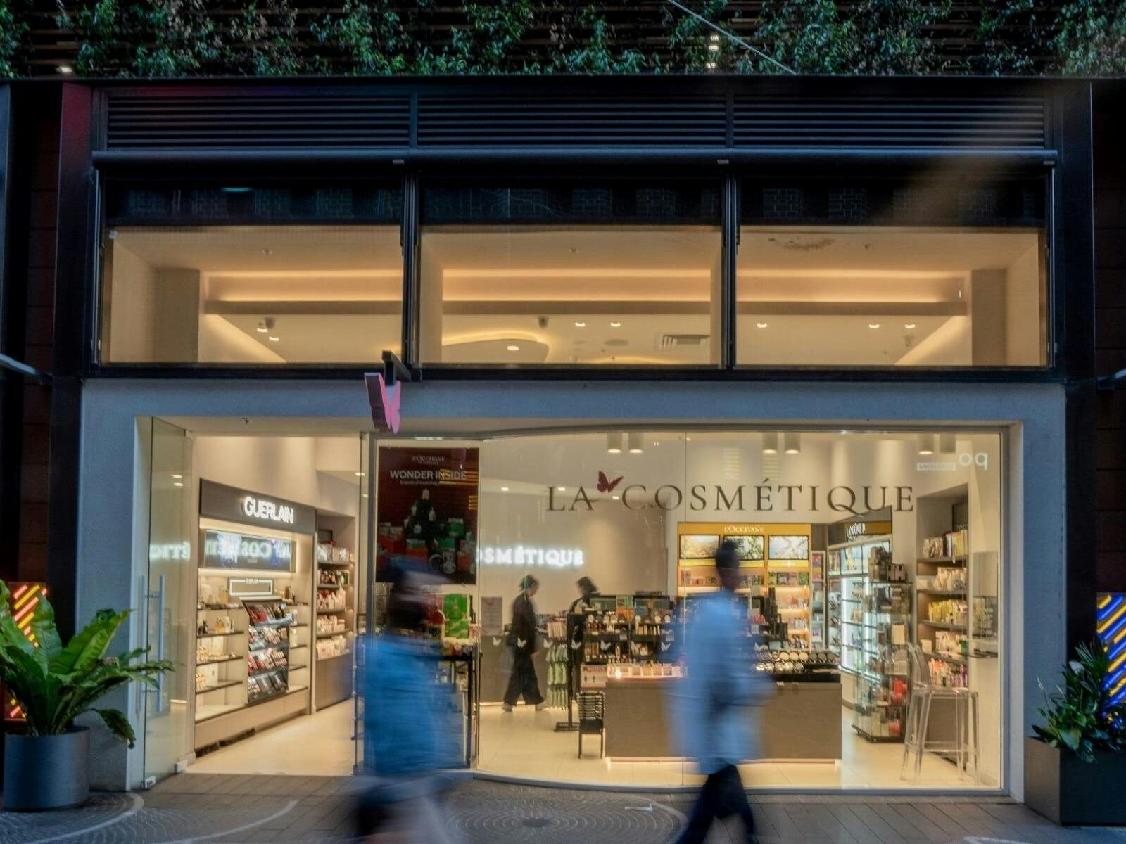 A shop front of La Cosmetique in Darling Square at evening