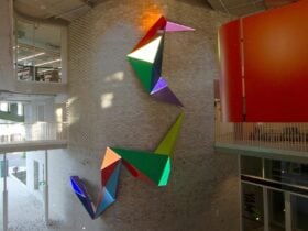 Let them feel the light, Emma Coulter, 2023. Colourful geometric forms suspended in an atrium.