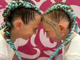 Two young girls with green manes attached to pony tales