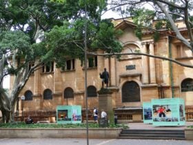 A statue in front of a sandstone building, with bright green cube installations on either side
