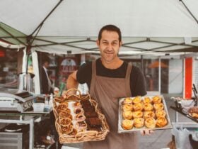 Stallholder from Courtney's Brasserie holding trays of cakes and tarts