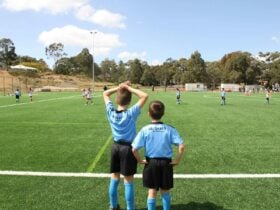 Two boys watch the game from the sidelines