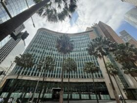 A large curved building with palm trees in front of it