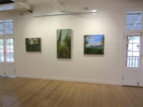 Three paintings on a white wall.