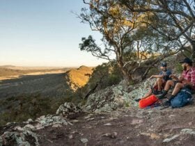 Two men sit on the ground at a viewpoint in The Rock Nature Reserve - Kengal Aboriginal Place.