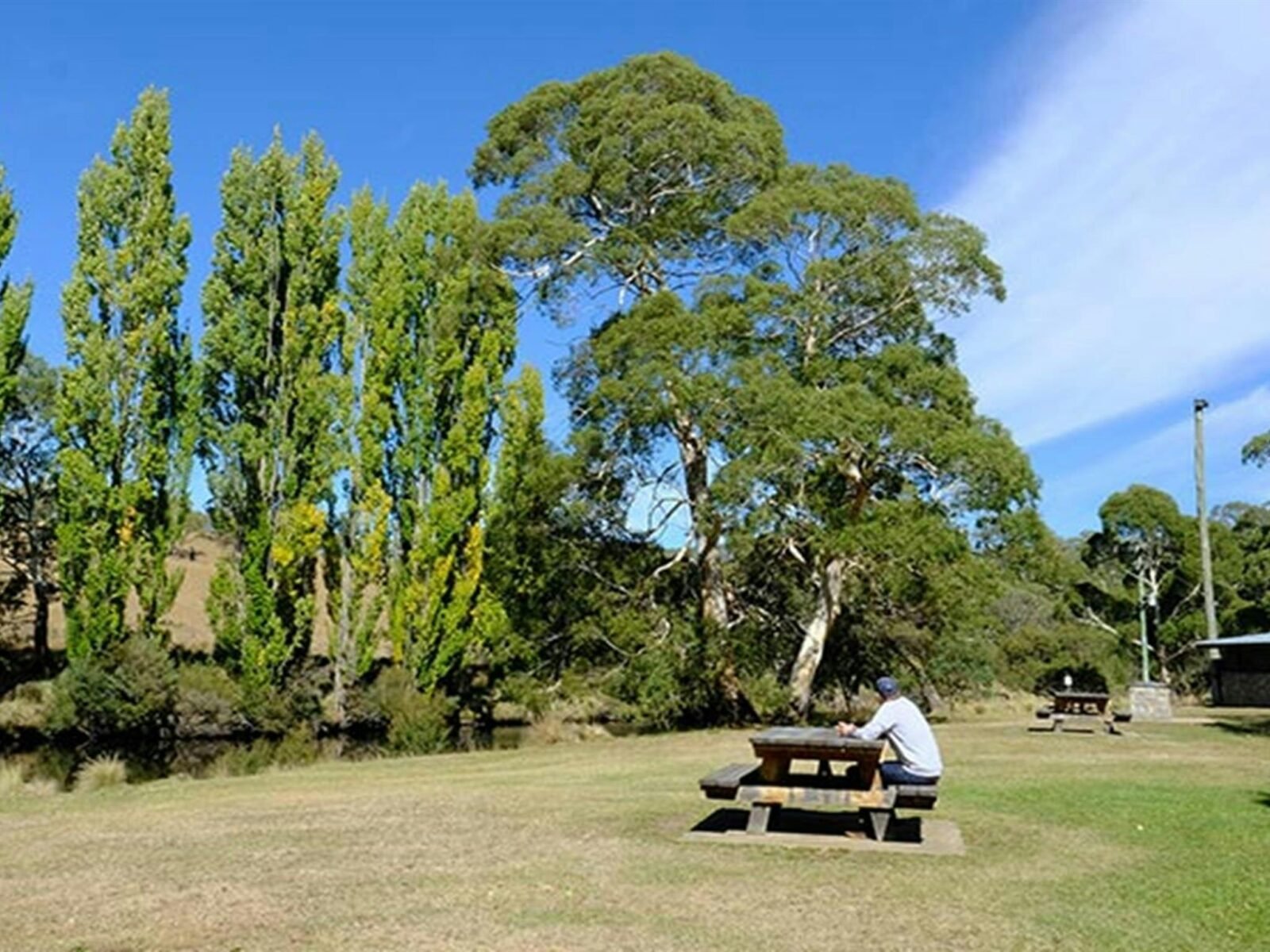 A man sits at a picnic table at Thredbo River picnic area in Kosciuszko National Park. Photo: Elinor