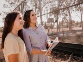 Mother and daughter smiling looking at huge bird aviary