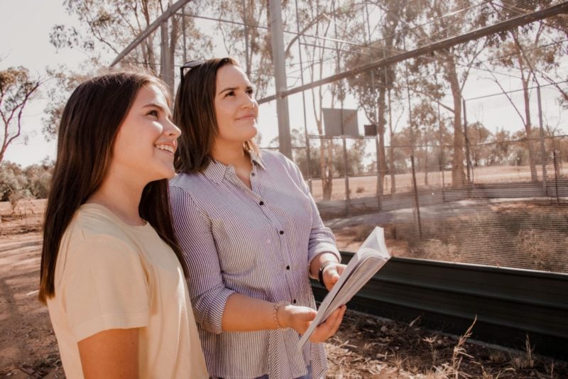 Mother and daughter smiling looking at huge bird aviary