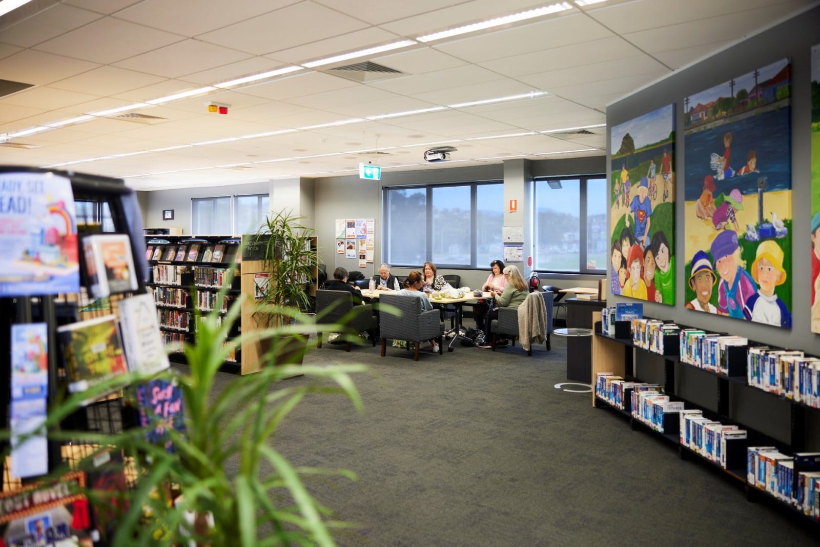 A group of people sitting around a table at Warrawong Library, talking and knitting.
