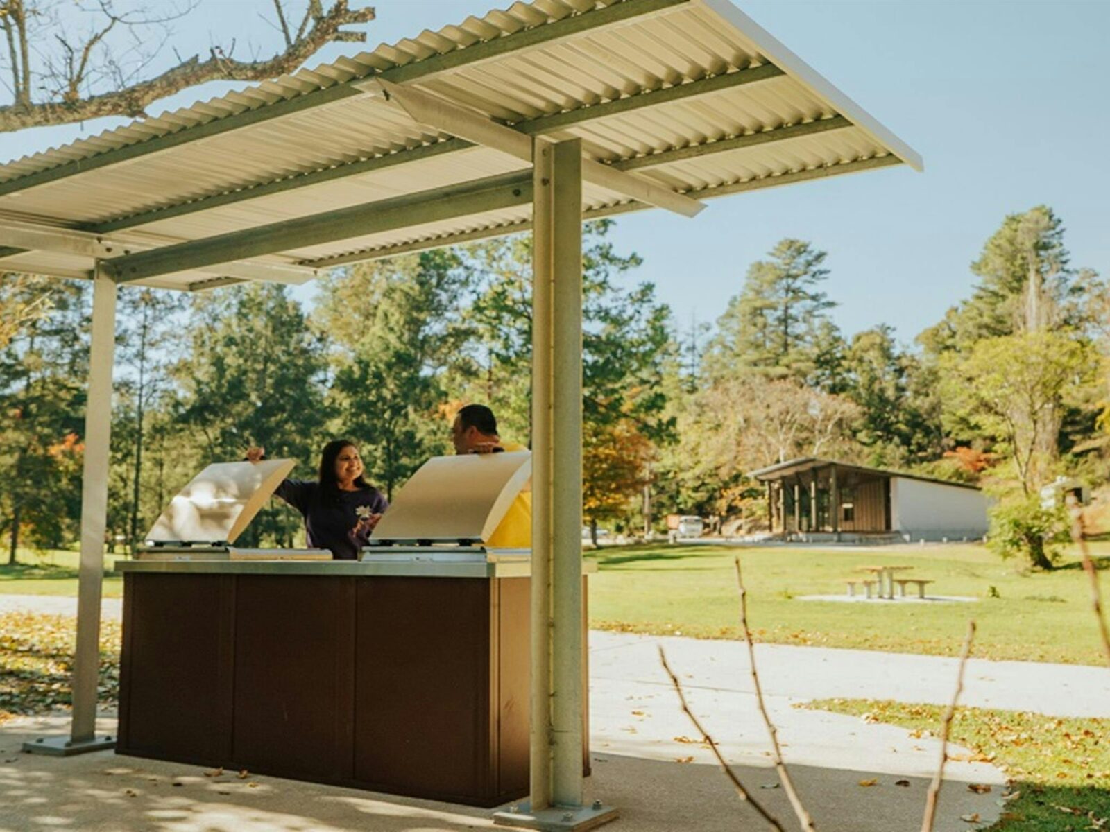 A couple chat while preparing lunch at the barbecue in Wombeyan picnic area. Credit: Remy Brand/DPE