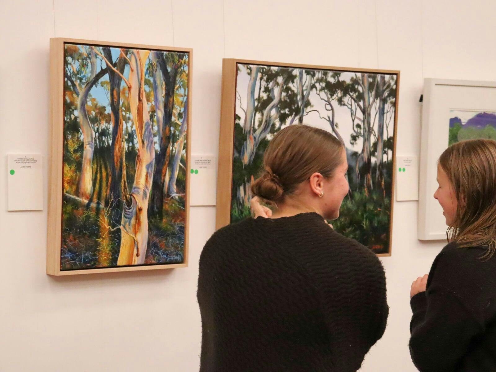 two women looking at artwork on wall
