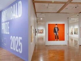 Archibald Prize 2025 hanging inside a gallery, including a bold red artwork in the centre.