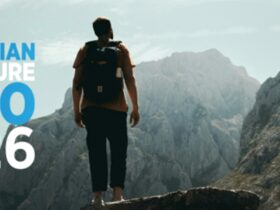 A man wearing a backpack standing on a mountain observing the view.