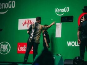 Darts player taking their turn, throwing dart at target.