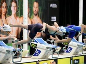Several swimmers are depicted diving into the pool to race at the 2025 Australian Trials
