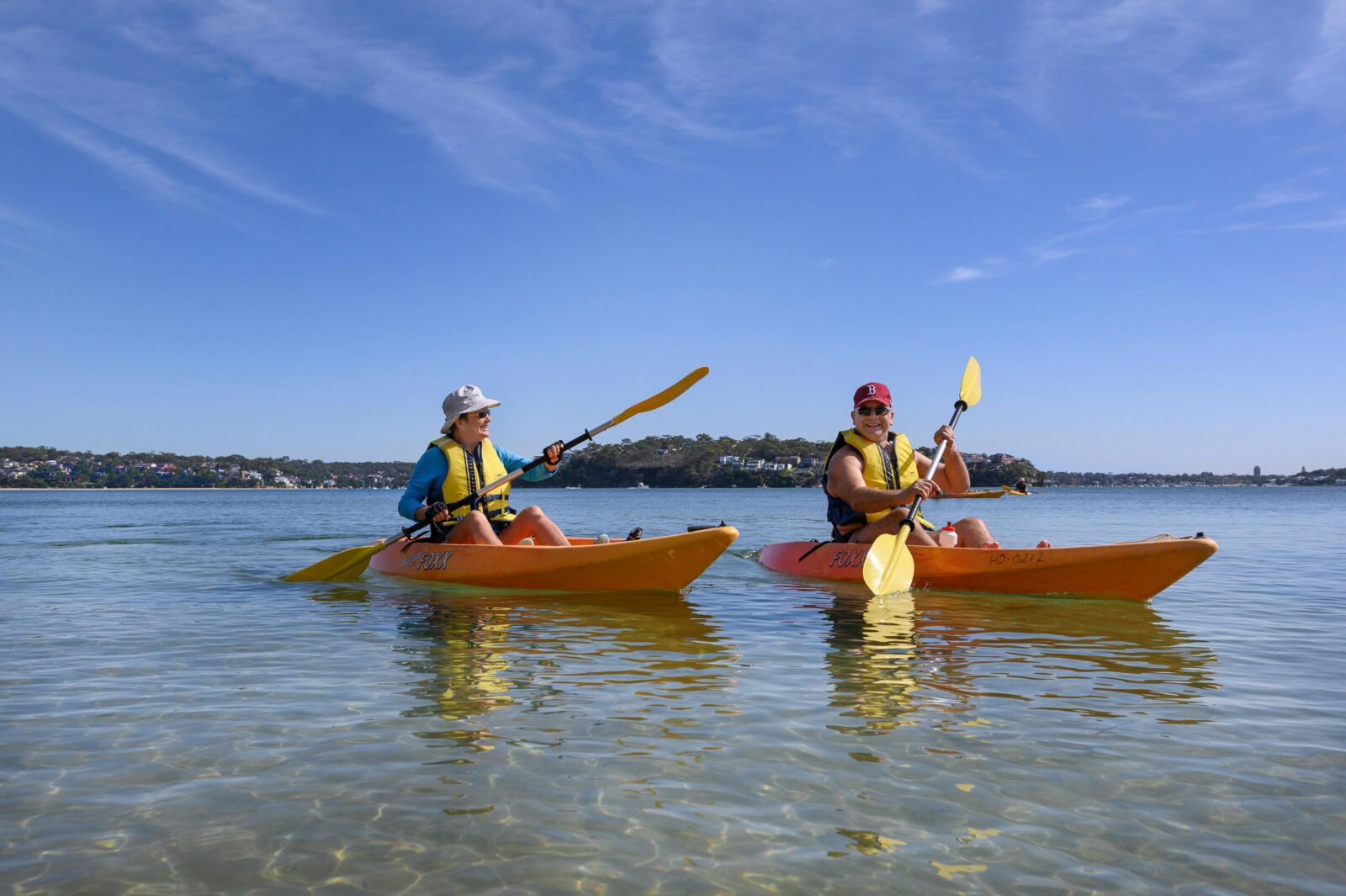 people kayaking along beach in single kayaks