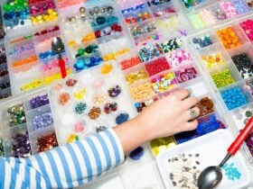 Hand reaching out to pick up beads above a colourful rainbow of second hand beads.