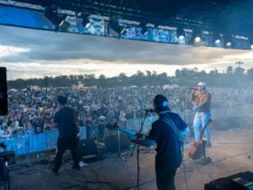 People on stage looking towards crowdat a festival
