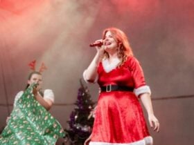 Carols by Candlelight Singing on Stage in a red dress