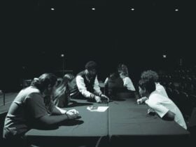Photograph of students sitting at a table in the performance studio attending a music workshop.