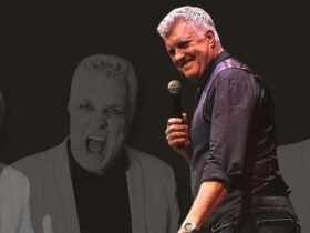 A man with grey hair looking behind his shoulder smiling with a microphone