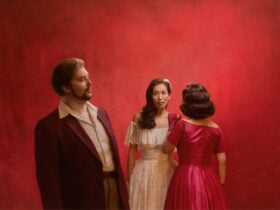 Three people stand against a red background