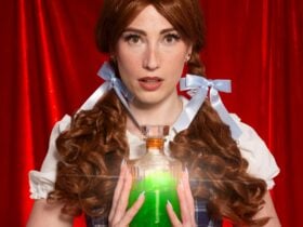 A red-haired woman in a Dorothy-style costume holding a glowing green potion.