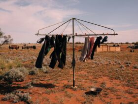Photograph of clothes hanging on a rotary line in a dry rural landscape with red dirt and open sky