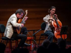 Guitarist and Cellist playing together inside a pavilion space